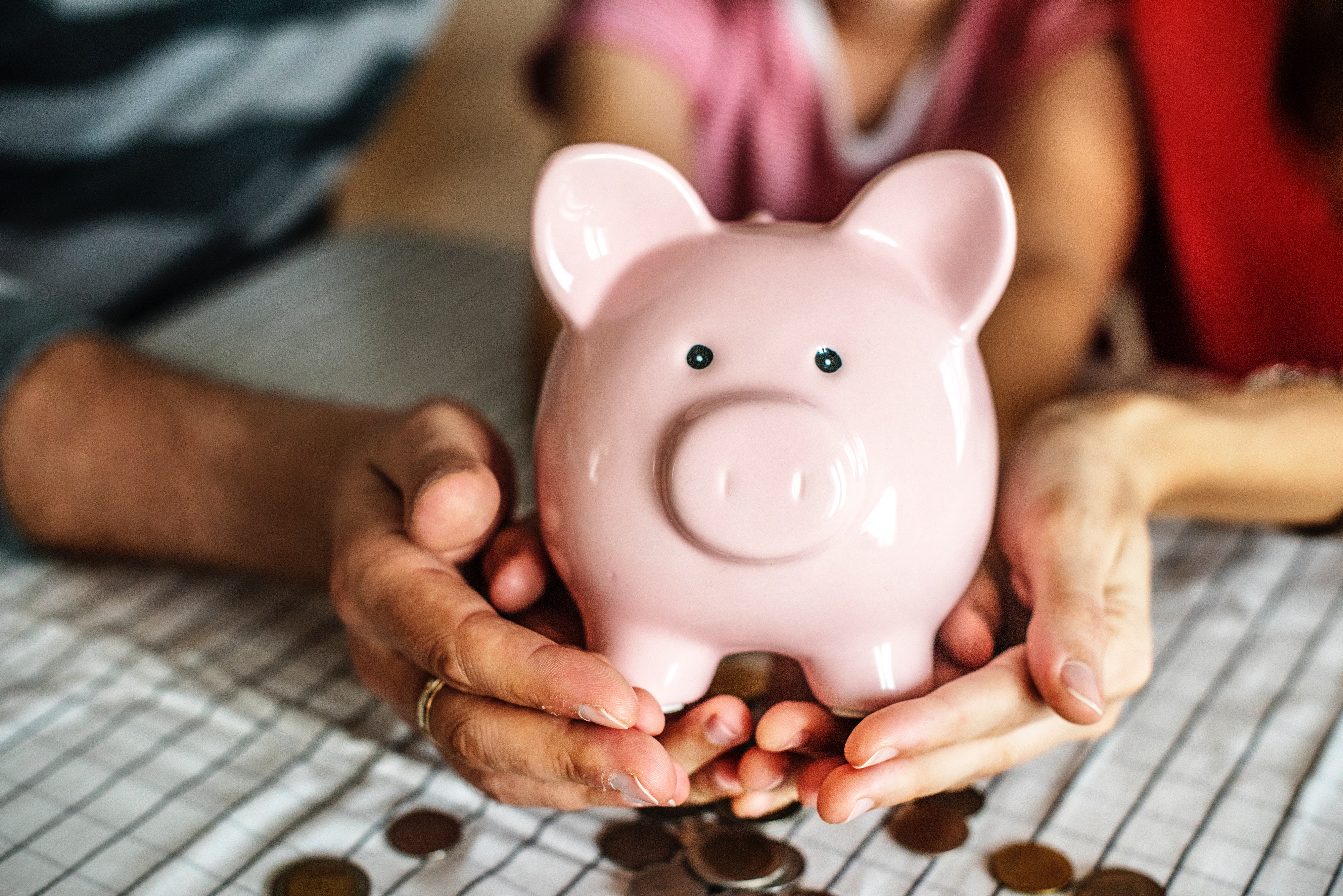 Pink Piggy Bank held by family with lose change below